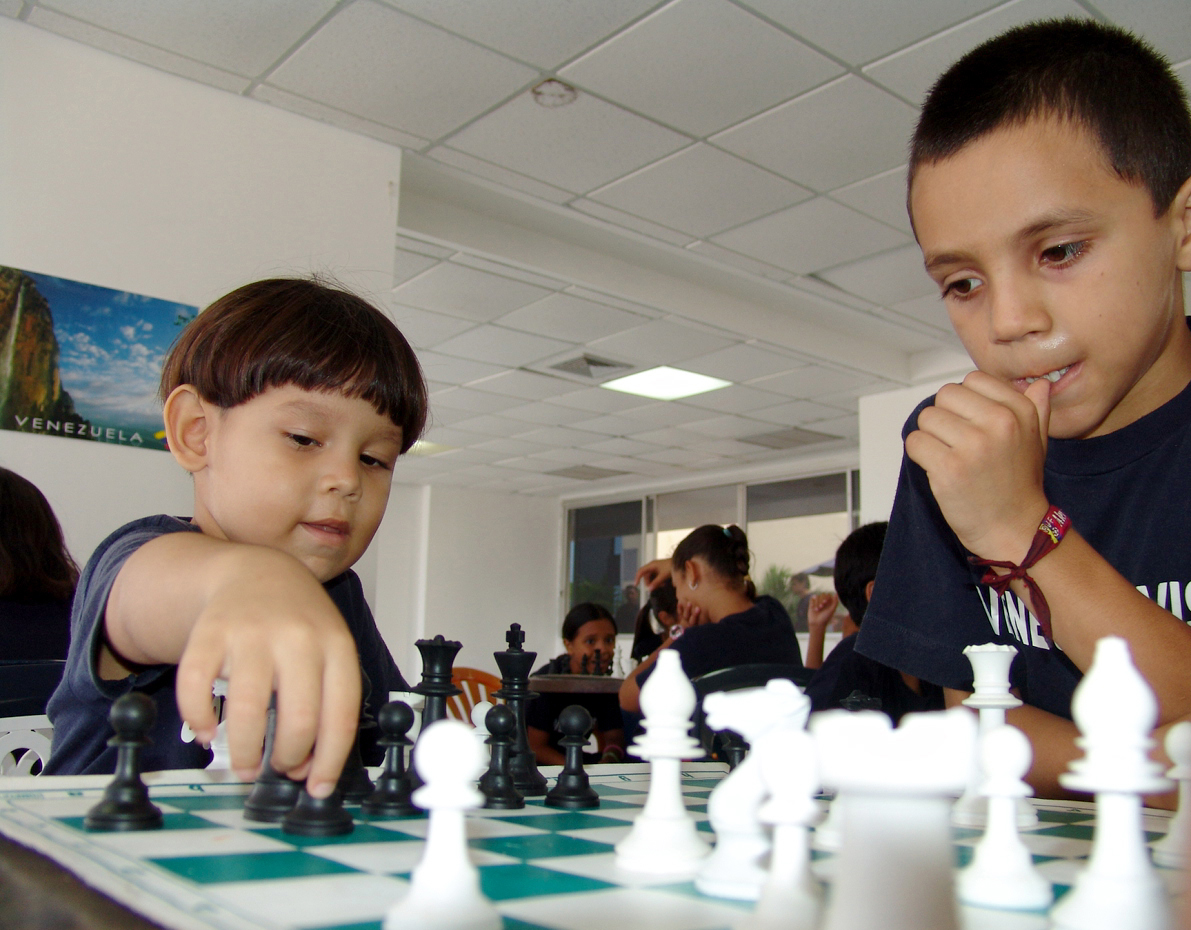 Two kids playing chess at a New East West Academy program